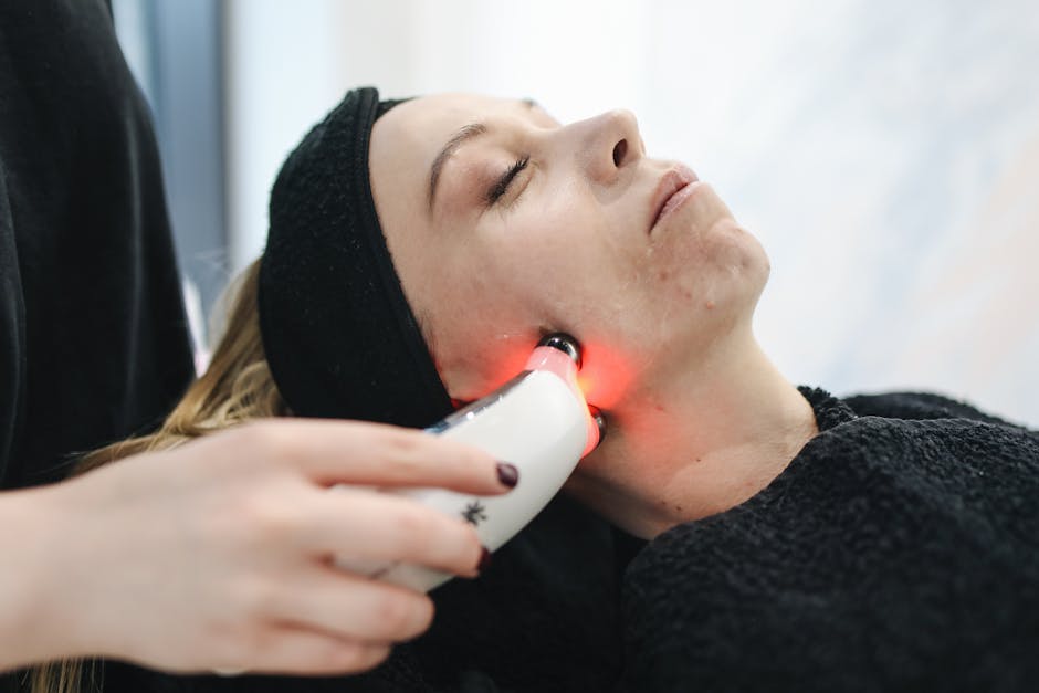 An adult woman receives a laser facial treatment in a modern skincare clinic