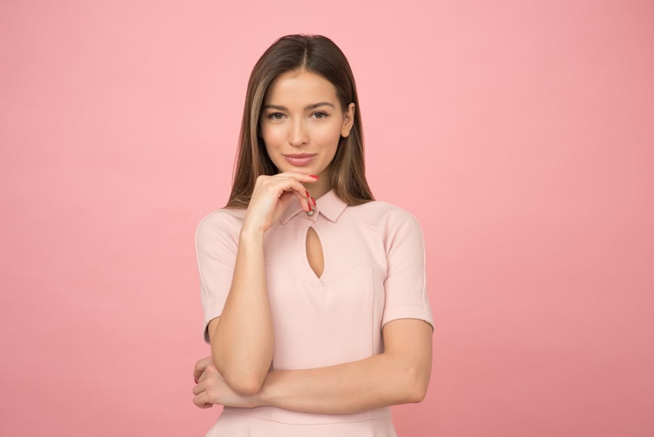 Portrait of a young woman posing elegantly in a studio with a pink background