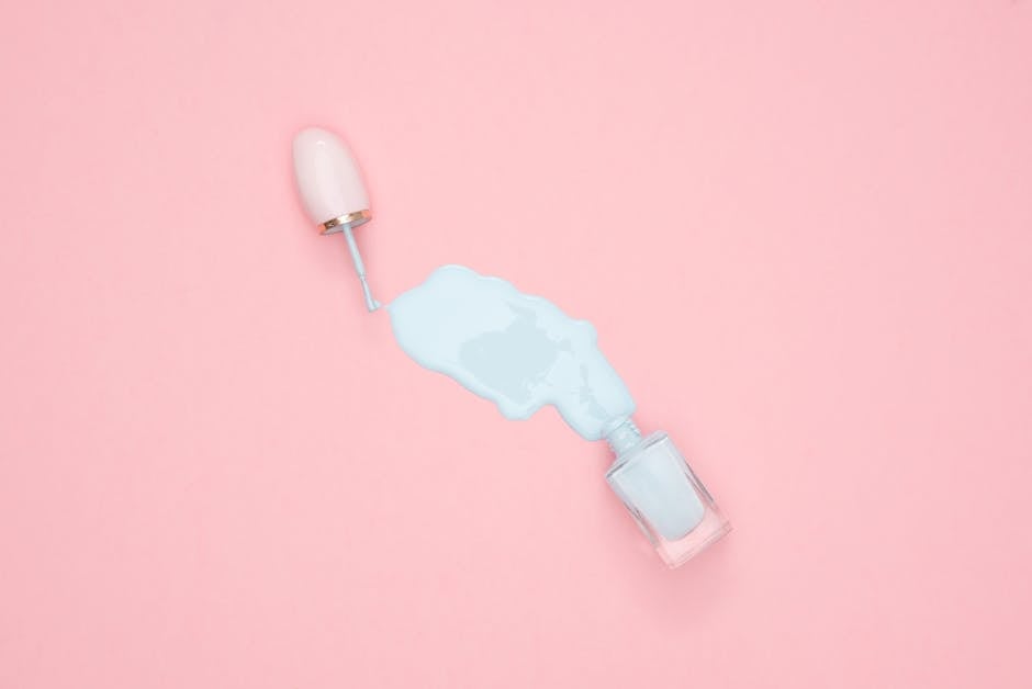 Artistic top view of blue nail polish spill on a pink background with copyspace