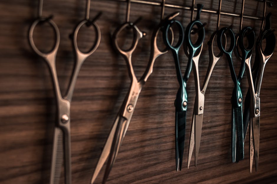 A collection of vintage barber scissors hanging on a wooden wall, showcasing sharp tools for hair cutting
